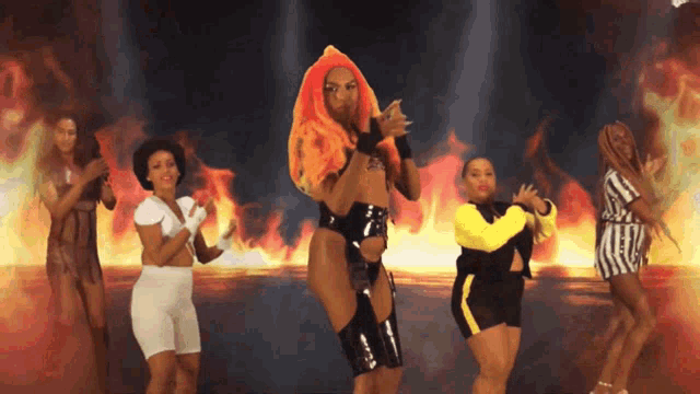 a group of women are dancing in front of a fire