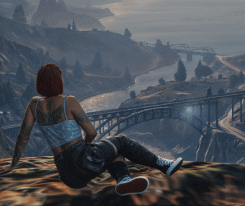 a woman with a tattoo on her back sits on top of a hill overlooking a bridge