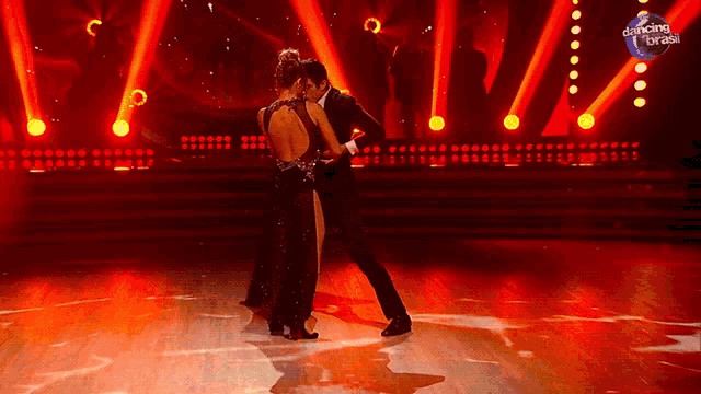 a man and a woman are dancing on a stage with a dancing brasil logo in the background