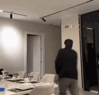 a man is standing in a room with a table and chairs and a door .