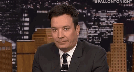 a man in a suit and tie is making a funny face while sitting on a stage .