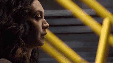 a close up of a woman 's face with a yellow railing behind her
