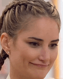 a close up of a woman 's face with braided hair and earrings .