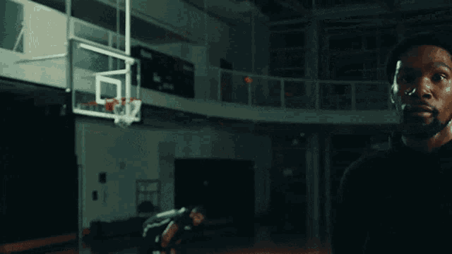 a man is standing in front of a basketball hoop .