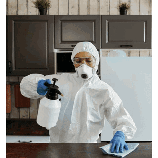 a person in a protective suit is cleaning a table