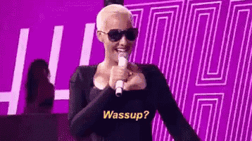 a woman wearing sunglasses and a black shirt is holding a microphone .