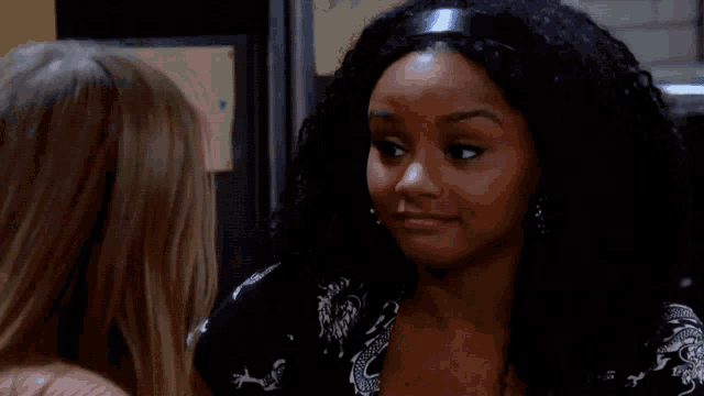 a woman in a brown sweater is smiling while talking to another woman