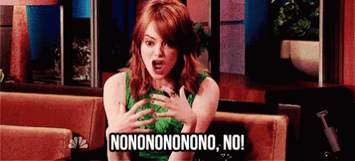 a woman in a green dress is sitting on a couch making a funny face and saying nononononono no !