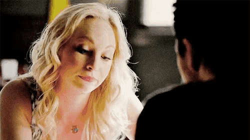 a woman is sitting at a table with a man and looking down at him .