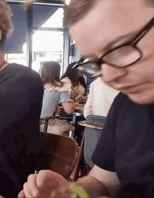 a man wearing glasses is sitting at a table with other people