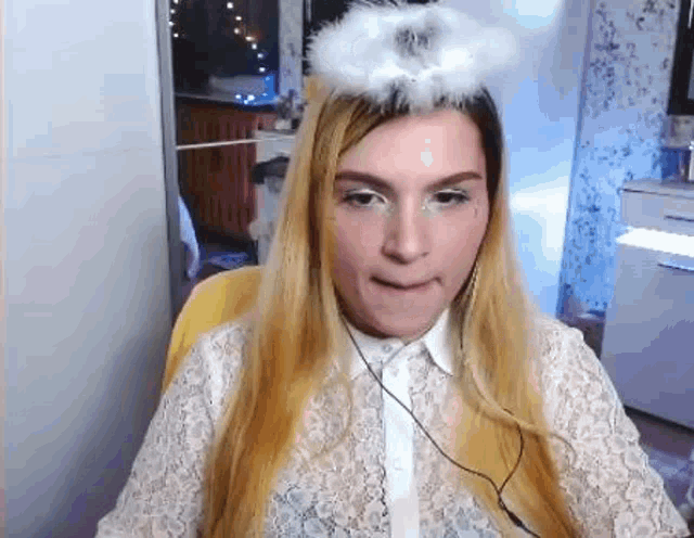 a woman wearing a white shirt and a white angel wing on her head is sitting in a chair .