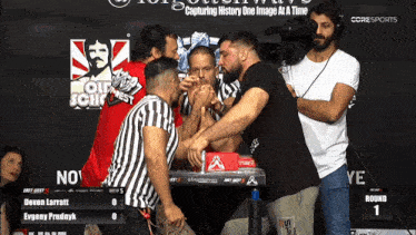 two men arm wrestling in front of a sign that says coresports