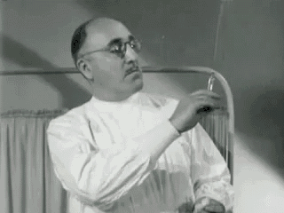 a black and white photo of a man in a lab coat holding a bottle .