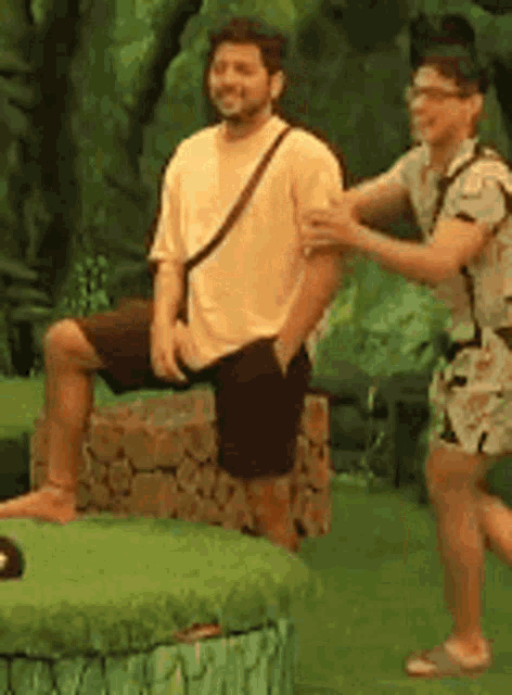 two men are standing next to each other on a green lawn .