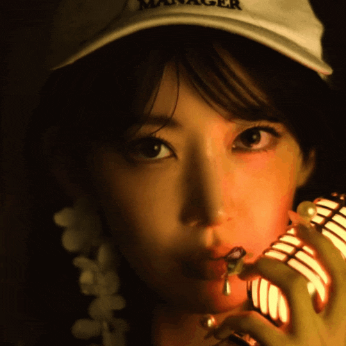 a woman wearing a hat that says manager holds a microphone