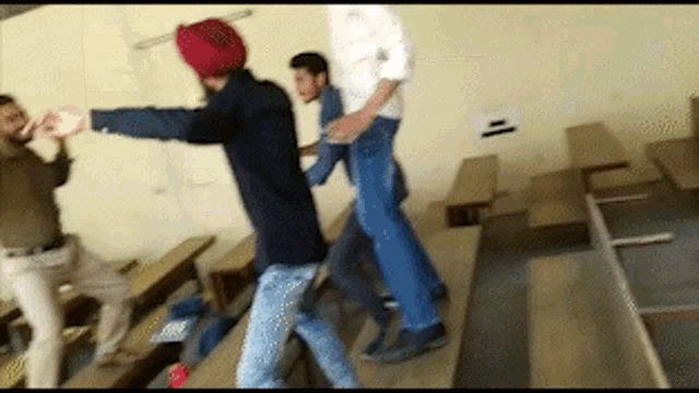 a man in a turban is dancing in a classroom with other men