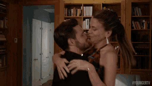 a man and woman are kissing in a living room .