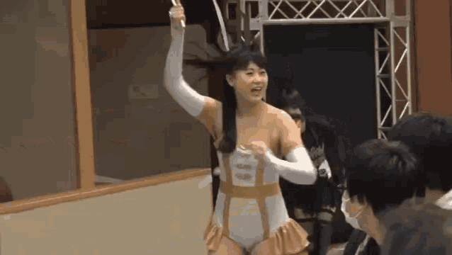 a woman in a wrestling outfit is standing in front of a crowd of people in a ring .