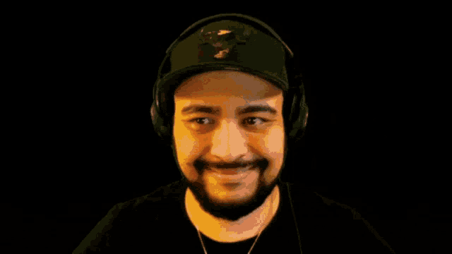 a man with a beard wearing headphones and a baseball cap