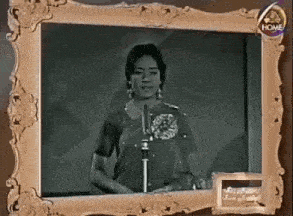 a black and white photo of a woman singing into a microphone .