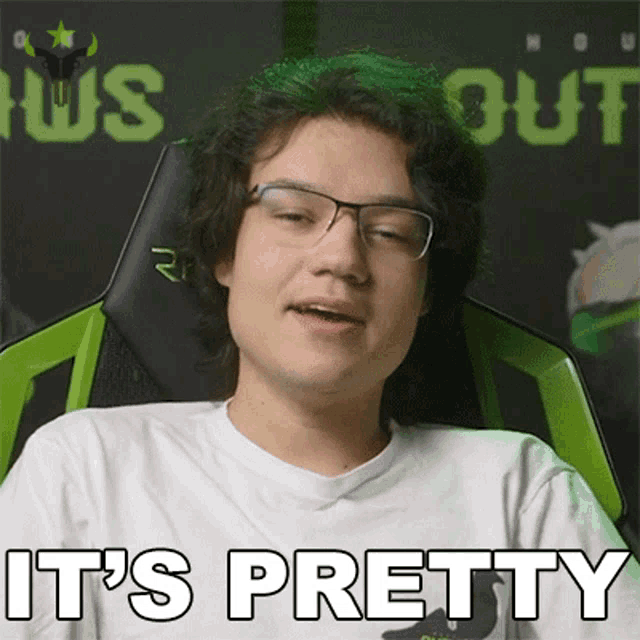 a young man wearing glasses and a white shirt says it 's pretty while sitting in a green chair