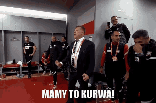 a group of men standing in a locker room with the words mamy to kurwa on the floor