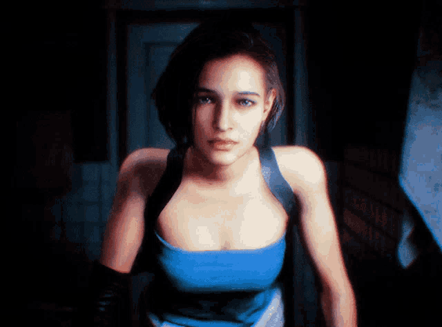 a woman in a blue tank top and black gloves stands in a dark room