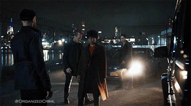 a group of men are standing in front of a car with the hashtag organized crime