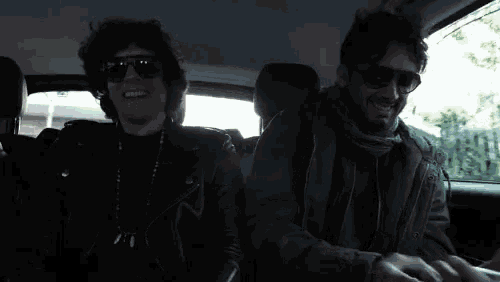 a man wearing sunglasses is sitting in the back seat of a car
