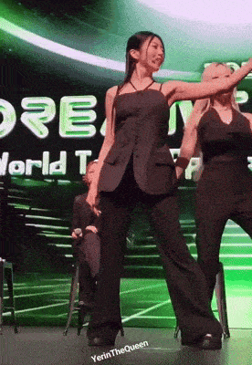 two women are dancing on a stage in front of a sign that says " world top "