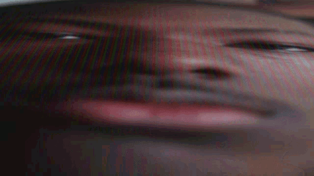 a close up of a man 's face with a blurred background and a red lip .