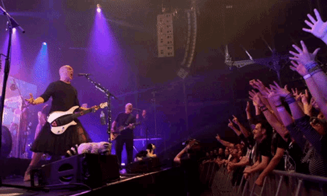 a man playing a guitar and singing into a microphone on stage