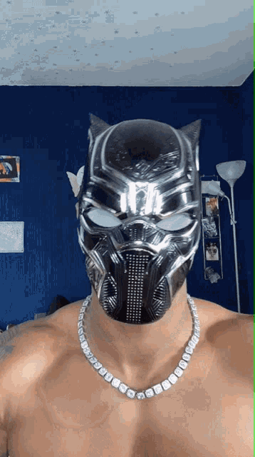 a shirtless man wearing a black panther mask and a necklace