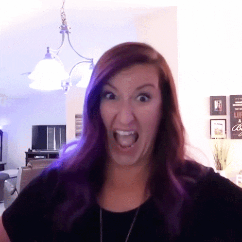 a woman with purple hair is making an angry face