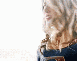 a woman in a superman costume is smiling while standing in front of a white background .