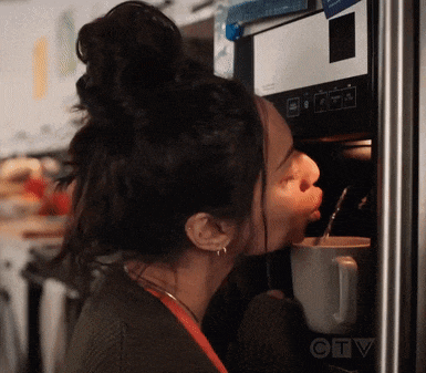 a woman is drinking from a mug in front of a microwave that says ctv on it