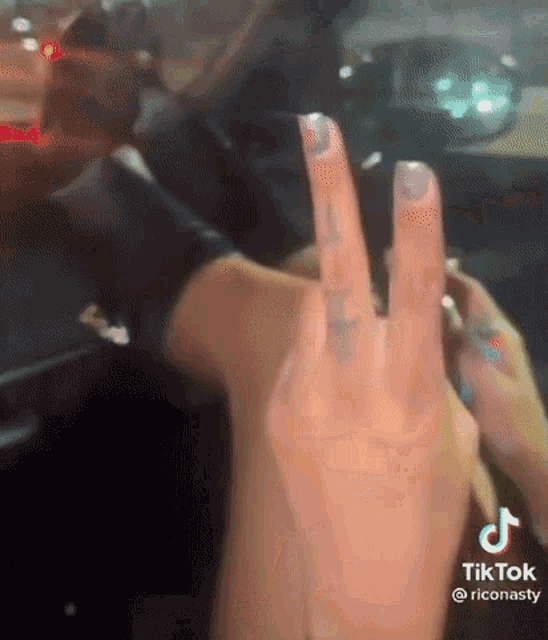 a woman is giving the middle finger in a car while driving .
