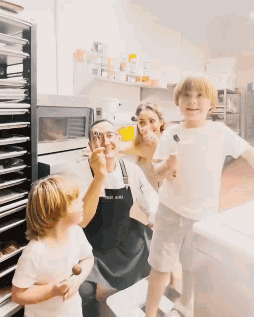 a woman wearing an apron that says petite bakery holds a child
