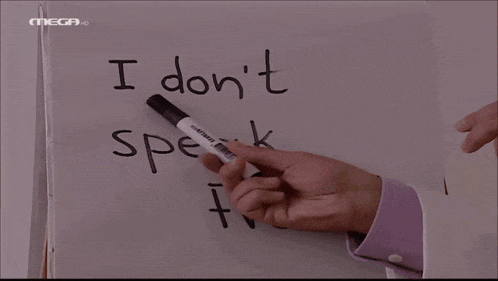 a man pointing at a white board that says " i don t speak french "