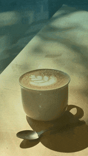 a cup of coffee on a table with a spoon in it