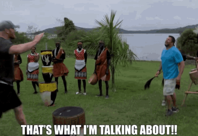 a man in a blue shirt says that 's what i 'm talking about in front of a group of african dancers