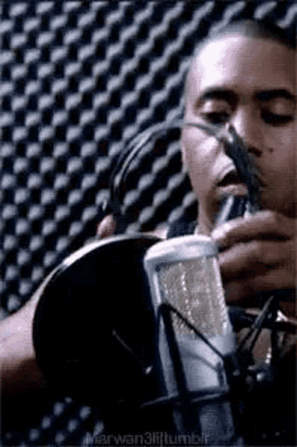 a man is singing into a microphone in a recording studio while wearing headphones .
