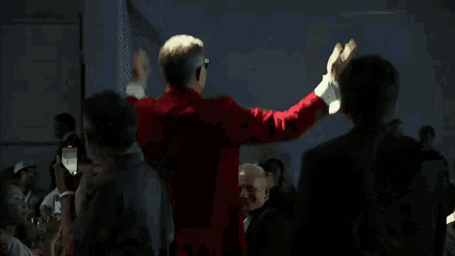 a man in a red suit stands in front of a crowd of people