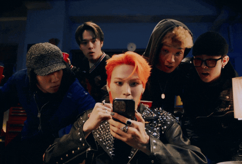 a man with red hair is looking at his phone while surrounded by other people