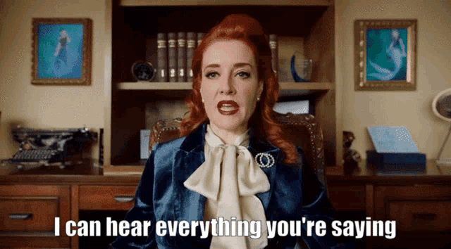 a woman says i can hear everything you 're saying in front of a bookshelf