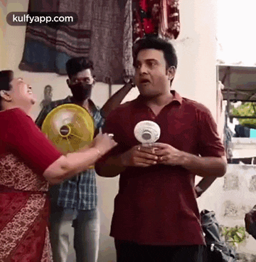 a man and a woman are standing next to each other holding a fan and talking to each other .