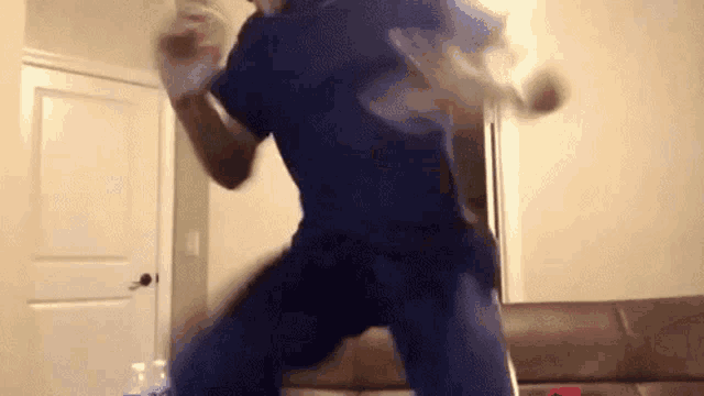 a man in a blue scrub top is jumping in a living room