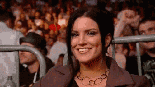 a woman is smiling while sitting in the stands of a boxing match .