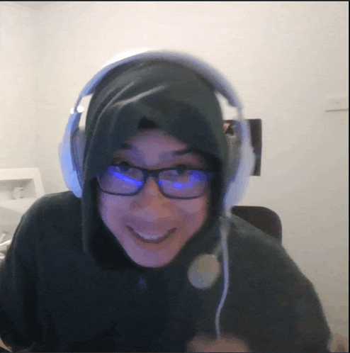 a person wearing a hoodie and headphones smiles at the camera