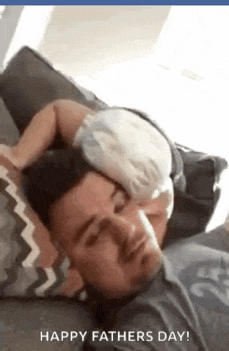 a baby is sleeping on a man 's head on a couch .